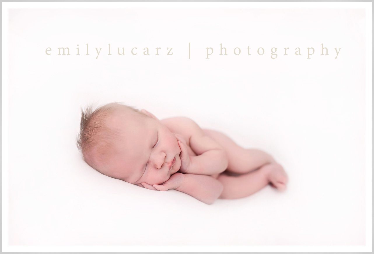 newborn pose on white blanket